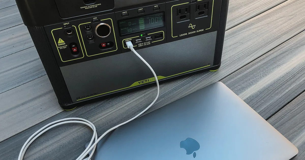 Tragbare Powerstation lädt während eines Stromausfalls einen Laptop auf einem Holztisch