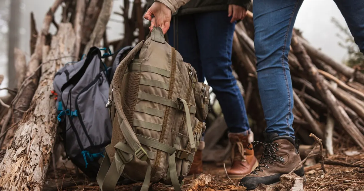 Notfallrucksack wird von zwei Personen im Wald aufgehoben — taktischer Rucksack für 72-Stunden-Krisenvorsorge